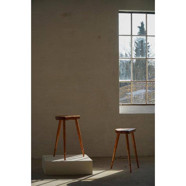 A fine pair of mid-century Danish tripod bar stools, exemplifying the clean lines and functional elegance characteristics...