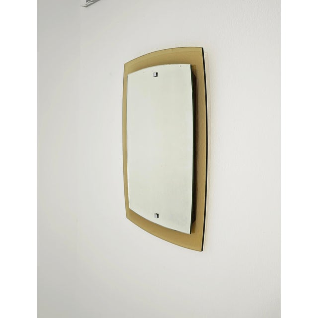 This Italian mid-century modern wall mirror, commonly attributed to the renowned Cristal Art manufacturing company, was...