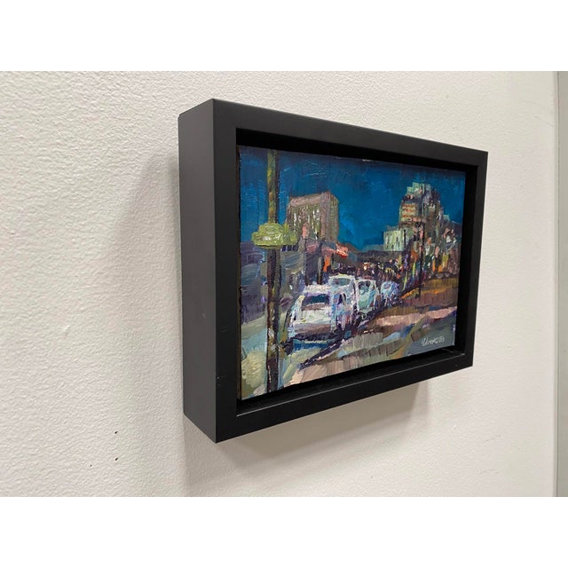 This nocturne captures a bustling urban scene illuminated by city lights, with cars lined up along the street under a deep...