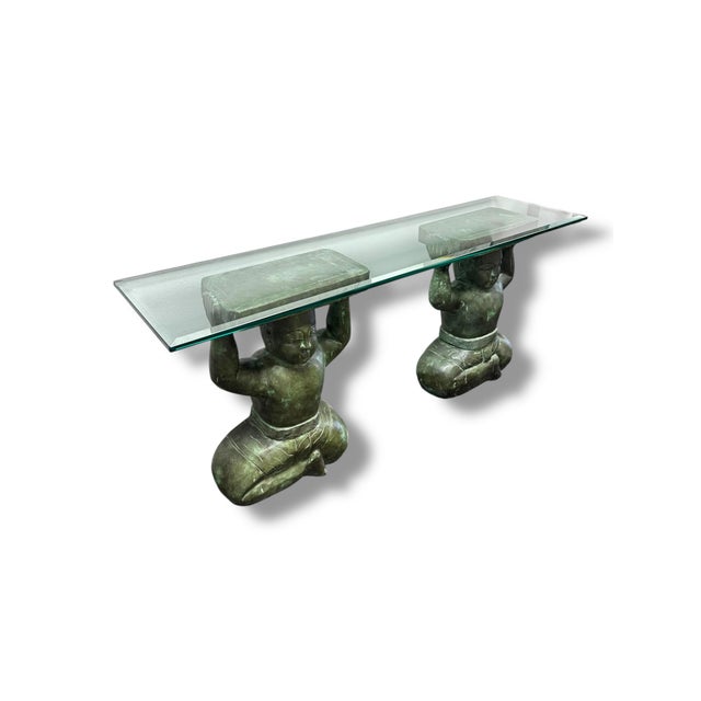 A striking statement piece, this pre-loved console table features a thick glass top supported by two sculptural Buddha-...