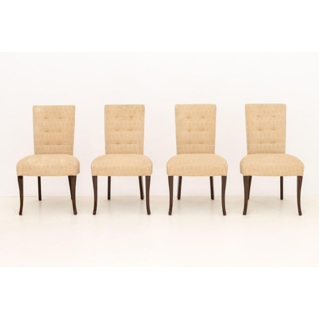 Set of Eight John Boone Tufted Beige Fabric Upholstered Dining Chairs, each upon dark stained wood legs with copper plaque...