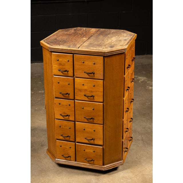 A rare oak rotating cabinet featuring 40 small drawers arranged across multiple faceted sides. Designed for apothecary,...