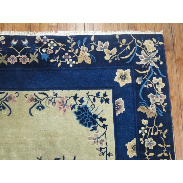 An early 20th-century floral Chinese rug in beige and navy Blue 6'2'' x 9' Peking rugs consist of designs that are simpler...