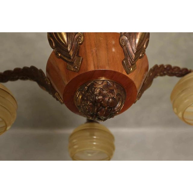 Original from the 1930s. The body of the chandelier is a combination of patinated cast brass and wood. Glass shades....