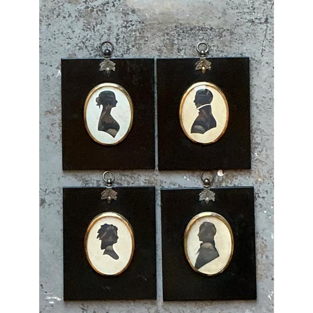 This vintage set of four miniature portraits presents a gallery of profile silhouettes, two women and two gentlemen, each...