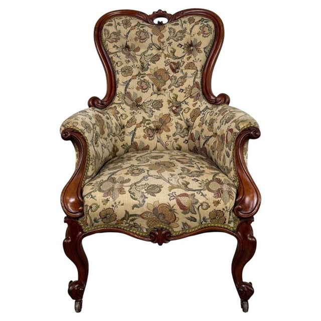 An elegant 19th-century English armchair, finely crafted from walnut and distinguished by its graceful cabriole legs, deep...