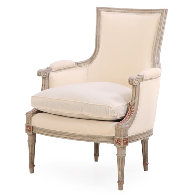 Elegant pair of Louis XVI style bergère chairs featuring a gray-painted wood frame with straight crests, low arms, and...