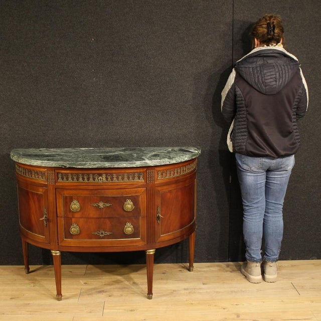 A French half-moon commode from the mid-20th century. A beautifully crafted Louis XVI-style furniture, finely carved and...