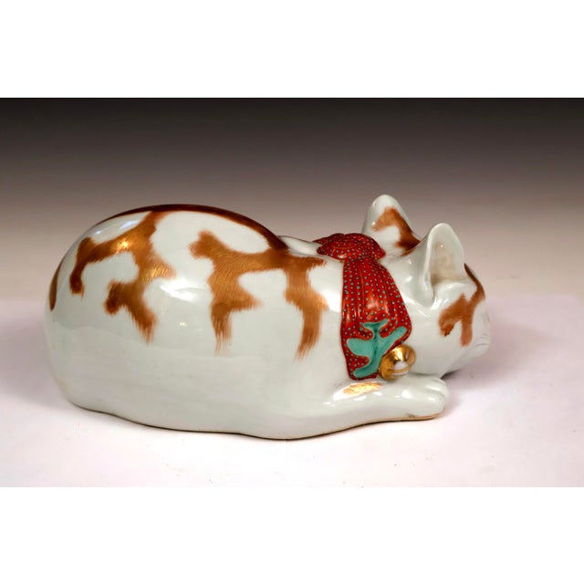 Large, nearly antique, Japanese Kutani porcelain sleeping cat figure with ribbon and bell tied around the neck. Circa...