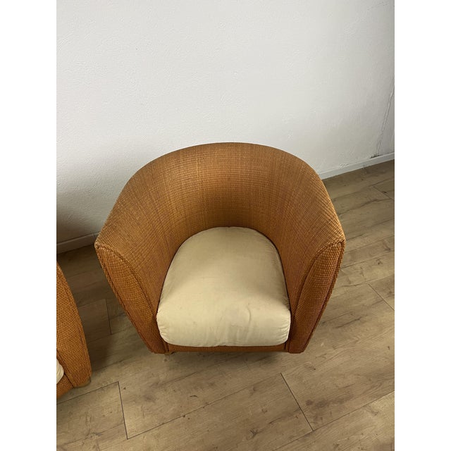 A pair of Bon Ton armchairs with a wraparound woven rattan frame and removable ecru fabric cushions, designed by Giuseppe...