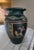 This rustic dark gray/black matte and green (top part) pottery vase features a design often reminiscent of Southwestern or...