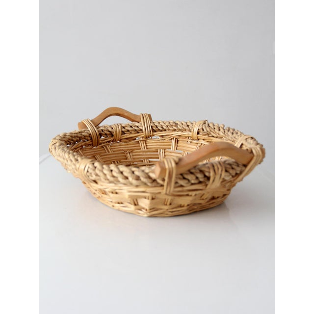 Beautifully woven vintage wicker basket with sculpted wooden handles, a thick braided rim, and a warm natural finish. Its...