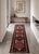A finely detailed runner rug featuring repeating geometric medallions framed by intricate border patterns. The combination...