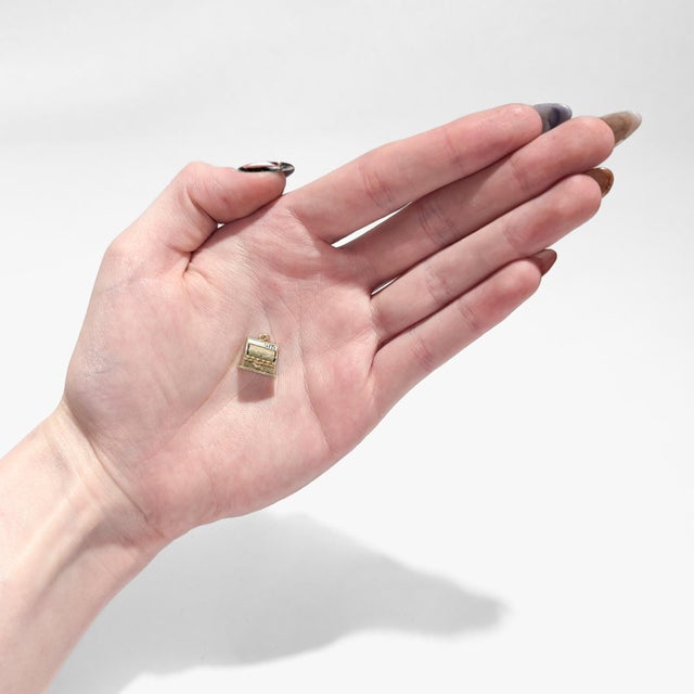 A fine vintage gold & enamel figural charm. In 14 karat yellow gold. In the form of a mechanical cash register with black...