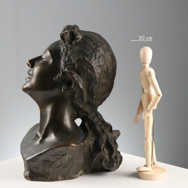 Bronze face of a young woman. Remarkable quality of the patination and expressive rendering of the features. The artist's...
