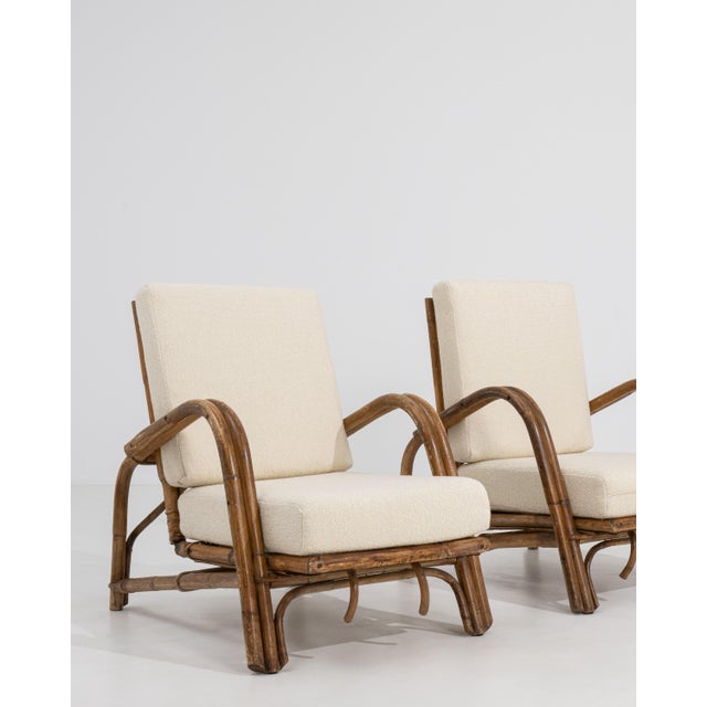 A pair of 20th century armchairs designed in the faux bamboo style, featuring wooden frames carved to imitate bamboo. The...