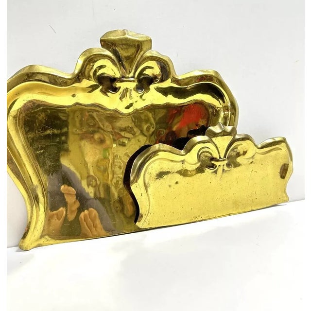 A charming vintage brass table crumber set featuring a Fleur-de-Lis motif, designed to elegantly sweep crumbs from the...