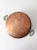 An antique heavy-gauge copper pan featuring twin brass handles and a gently rounded base. The substantial copper...