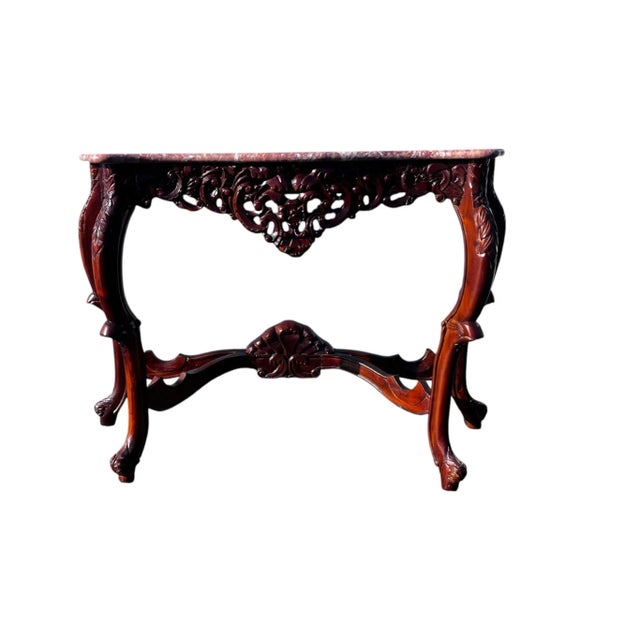 A gorgeous Rococo-style, hand-carved wooden console table with a spectacular pink-hued marble top, hand-crafted by an...