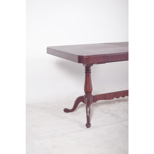 Extendable dining table in walnut and walnut root. Rectangular in shape, with rounded corners, resting on two turned...