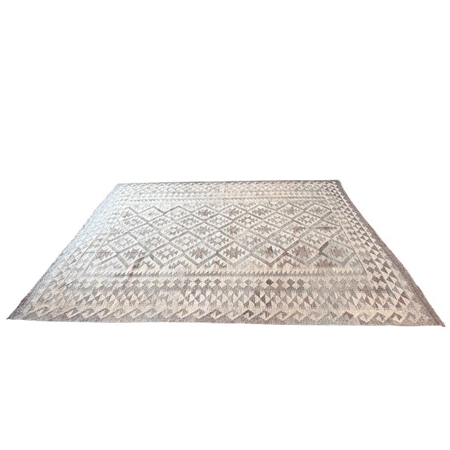This beautifully handwoven wool kilim rug features a timeless geometric pattern composed of diamond motifs and tribal-...
