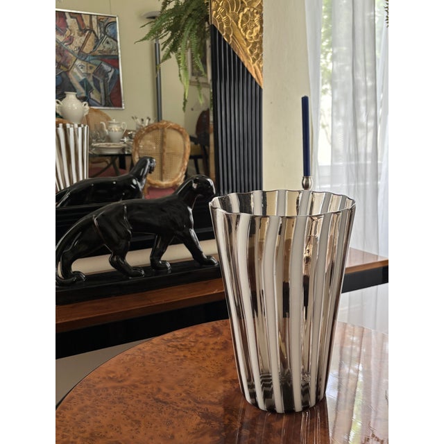 The vase, made of fused rods of milk glass and anthracite-colored glass, is signed Venini (Venini Italy, engraved) and...