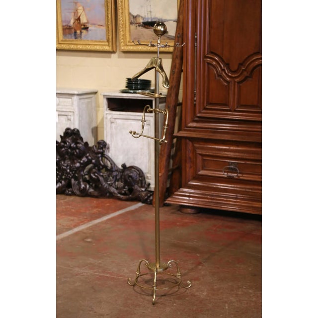 This antique brass and metal hall tree was crafted in France, circa 1920. Standing on three thin scrolled legs, the tall...