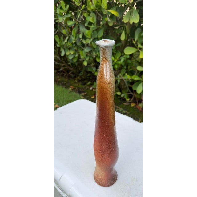 Hand-thrown studio pottery vase with a tall sculptural form and earth tone drip glaze in rust, ochre, cream, and gray....