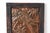 A hand-worked copper repoussé wall plaque depicting a parrot among stylized blooms, framed in rustic stained wood. Rich...
