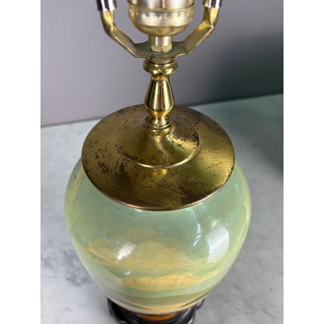 Vintage lamp painted village scene on a vase table lamp with wooden base and brass lid. Working corded electric condition.