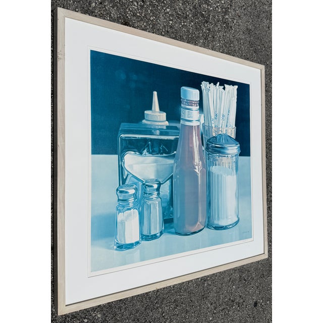 Monochromatic, blue-toned framed print of "Still Life with Straws" (1978) by the prominent American photorealist artist...