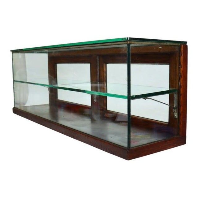 This antique country store display case, dating to approximately 1910, features a robust oak frame with beveled glass...