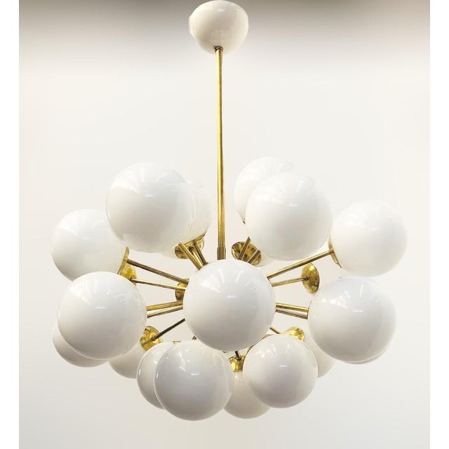 Italian oval shaped sputnik chandelier with 24 glossy white Murano glass globes mounted on brass frame in unlacquered...