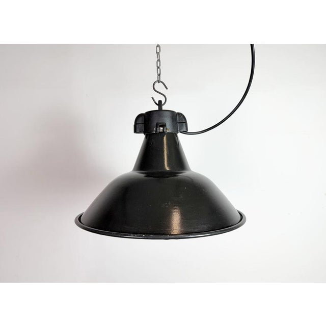 Industrial black enamel pendant light made in former Czechoslovakia during the 1950s. White enamel inside the shade. Cast...