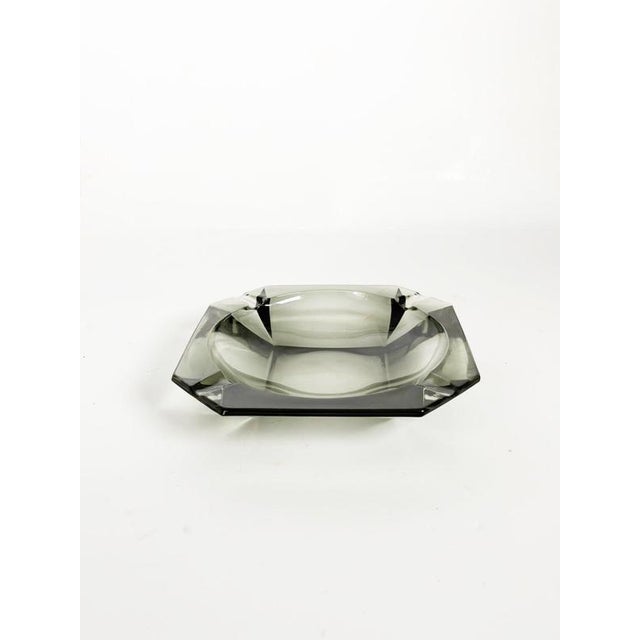 French glass ashtray dating from the 1970s, featuring a substantial geometric form in smoky grey glass. The thick molded...