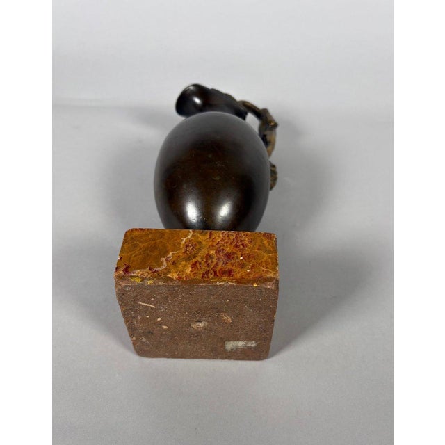Patinated bronze oinochoe . The handle is sculpted with a depiction of an ephebe entwined with two serpents and resting on...