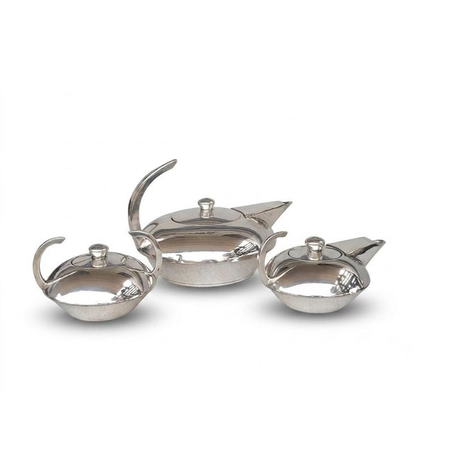 This striking vintage three-piece silver-plated tea service embodies the timeless elegance of the Art Deco and Streamline...