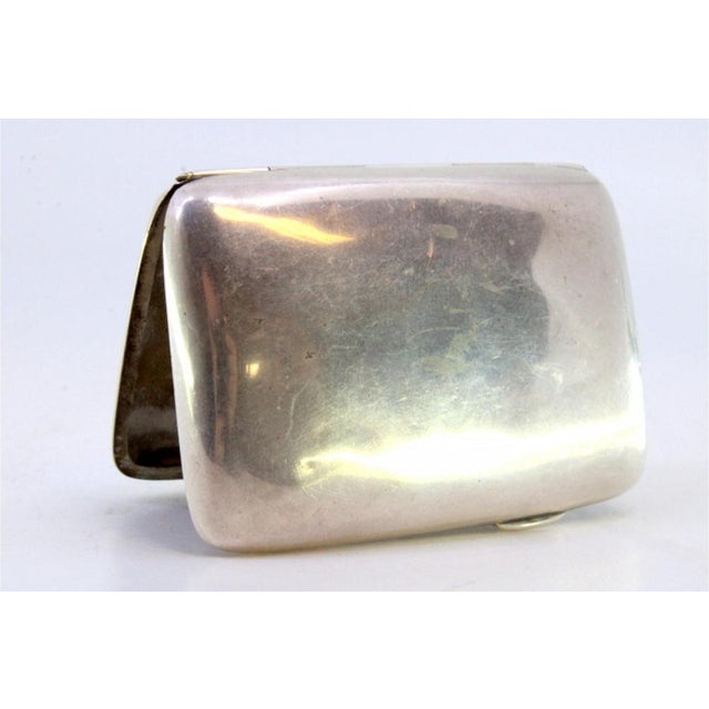 Smooth silver cigarette case with curved shape with opening application and two interior strips to hold cigarettes This...