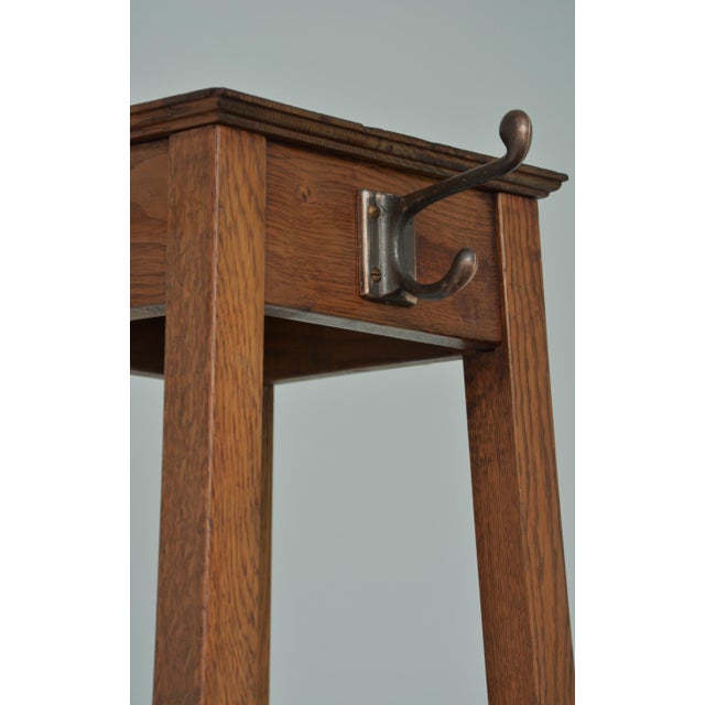 Stylish arts and crafts solid oak coat stand, having four shaped double hooks to each side on four outswept supports...