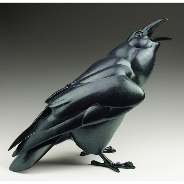 This bronze sculpture captures a raven in mid-caw, its form exuding a sense of vitality and presence. The smooth, dark...