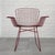 A modernist wire armchair crafted from robust steel wire painted in a deep red color. The chair is constructed from a sled...