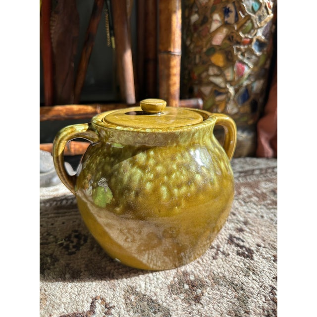 A richly glazed mid-century USA pottery lidded sugar bowl, featuring a warm mustard base layered with organic mossy green...