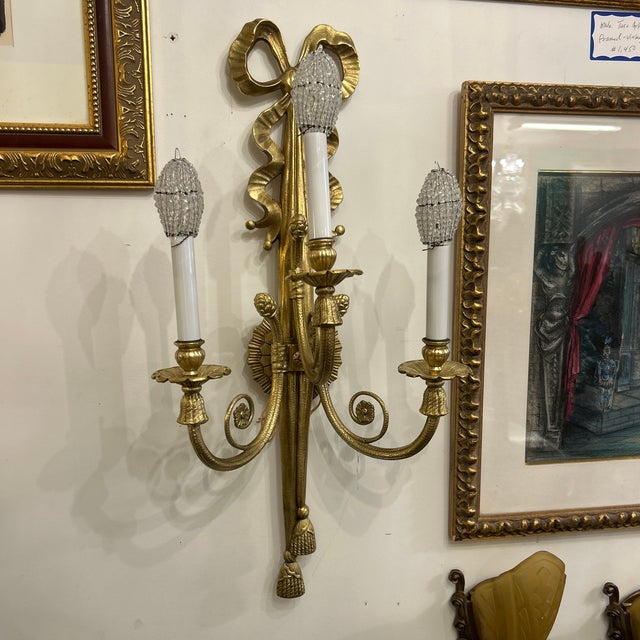 Ribbon and tassel brass finish metal wall sconce. It is traditional and has a lot of detail including the glass strands...