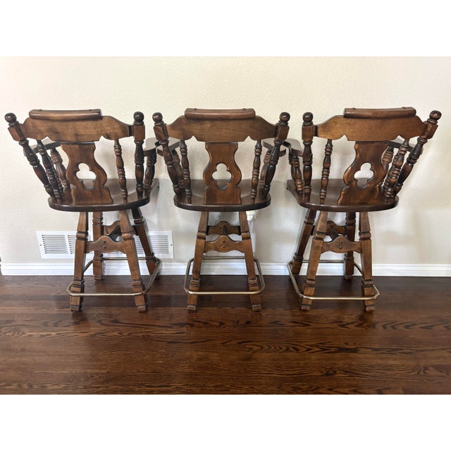 A handsome set of three vintage oak swivel bar stools dating to March 1981, based on original production markings found on...