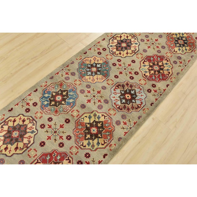 A tribal Caucasian Kazak runner hand-knotted with an all-wool pile on a cotton foundation. This oriental rug features rows...