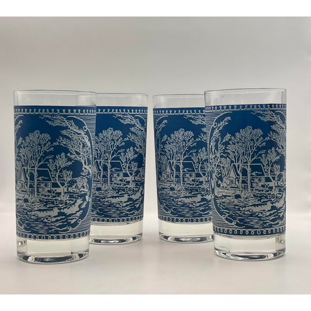 A set of four blue and white line-work tumblers featuring a charming forested farmstead vignette set in a a frame of...
