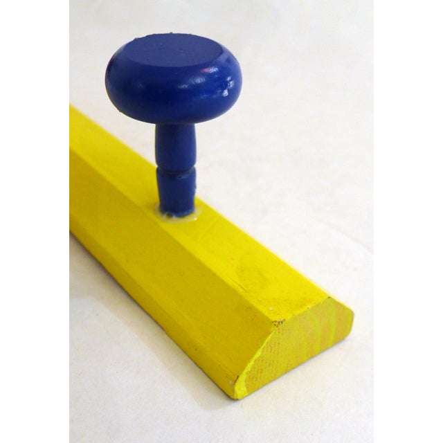 Wall-mounted coat rack in the shape of a yellow pencil, with 3 round hooks in red, green, and blue; made of painted pine...