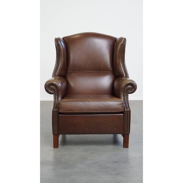Offered this large, classic dark brown smooth cowhide leather chesterfield ear chair in English style. This beautiful...