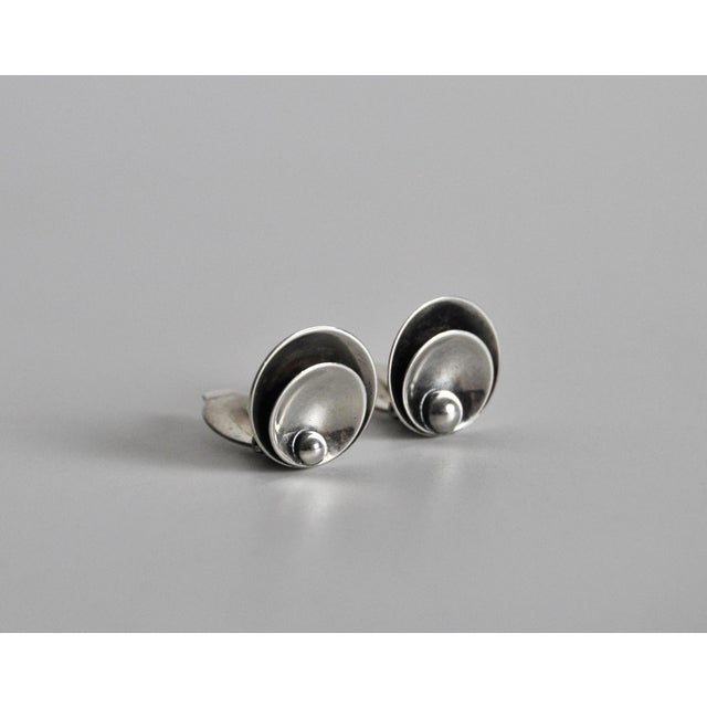 Modernist earclips with a highly polished finish in sterling silver, designed and made by the Danish goldsmith Hermann...