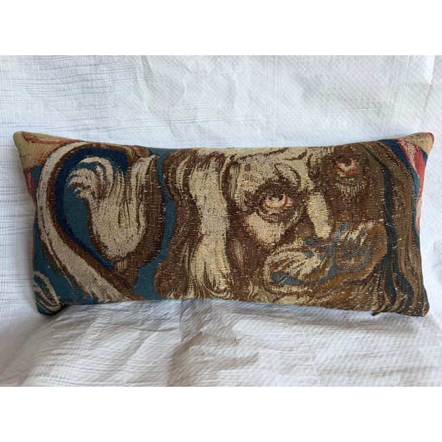 This elongated decorative pillow is crafted from a tapestry fragment featuring a complex figural composition defined by...